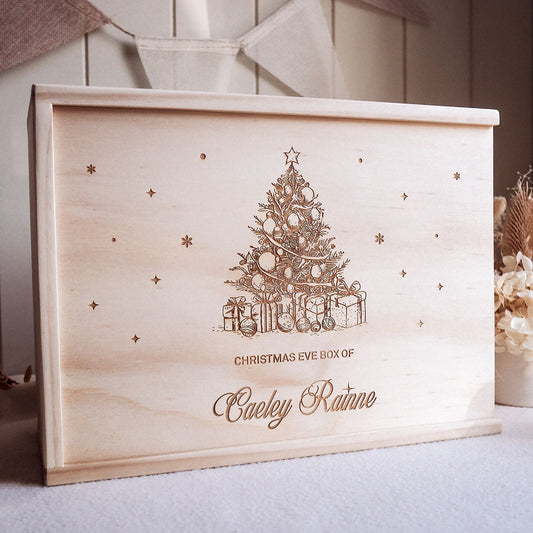 Wooden Christmas Eve box with engraved Christmas tree and presents design, featuring the name 'Caeley Rainne'.