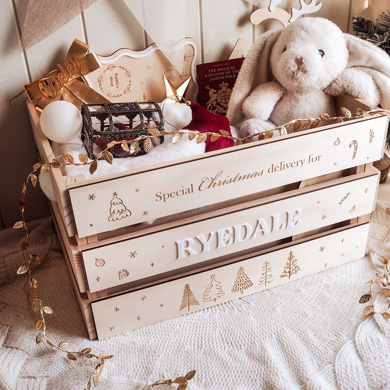 Wooden crate labeled 'Special Christmas delivery for RYEDALE' with decorative items on a soft surface.