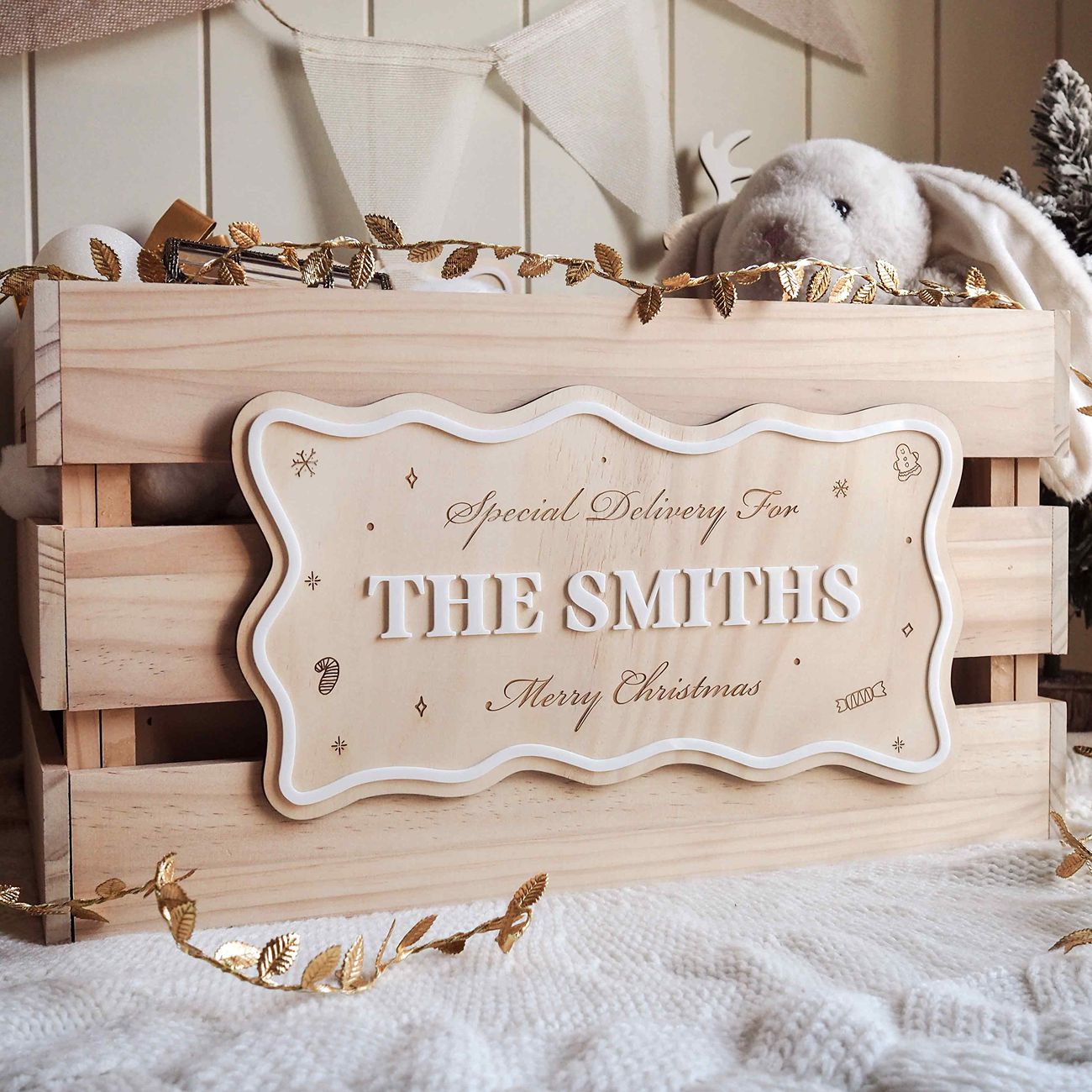 Wooden gift box with 'Special Delivery For THE SMITHS Merry Christmas' sign, surrounded by decorative elements.
