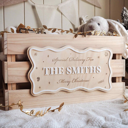 Wooden gift box with 'Special Delivery For THE SMITHS Merry Christmas' sign, surrounded by decorative elements.