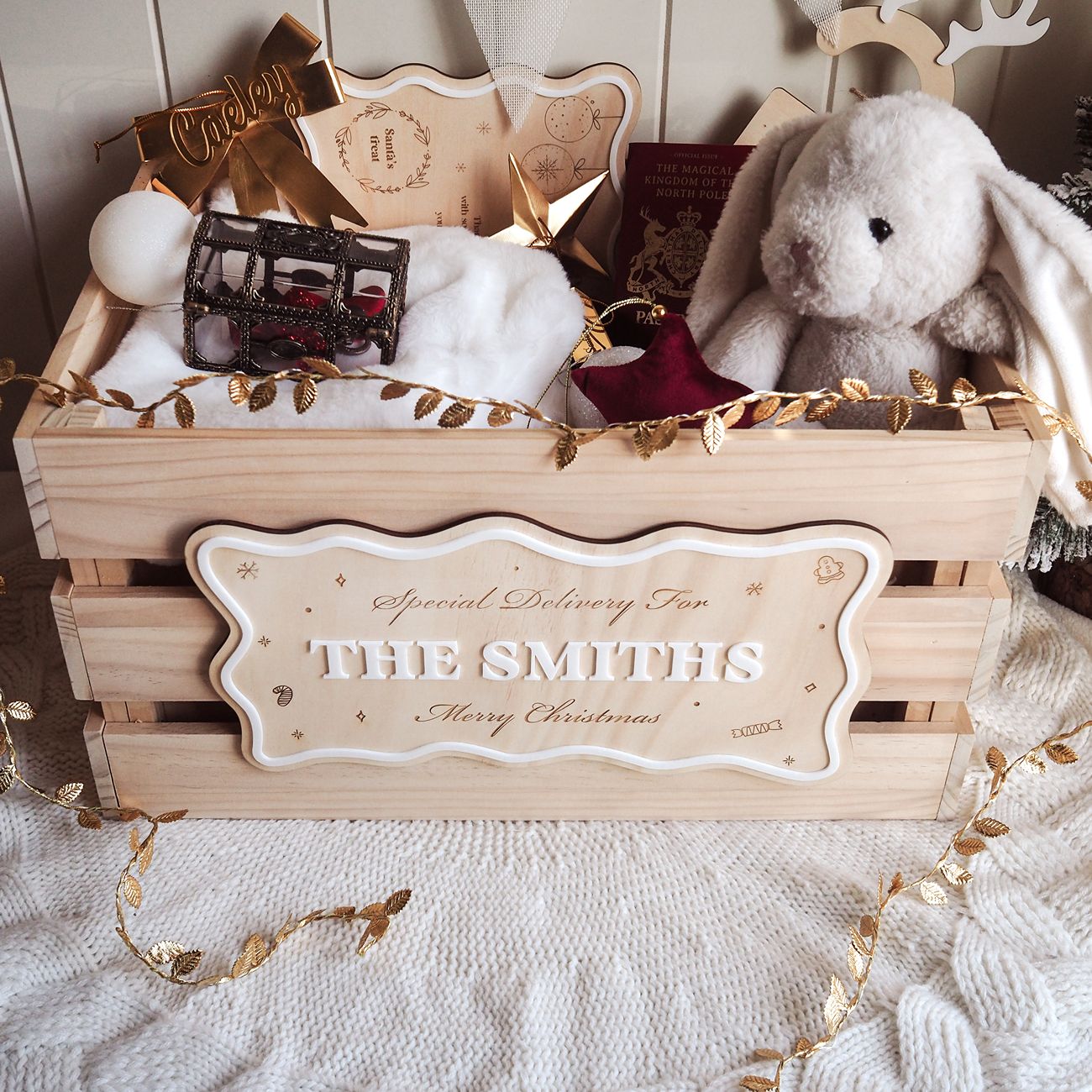 Wooden gift box with 'Special Delivery for THE SMITHS' label, stuffed bunny, and decorative items on a soft surface.