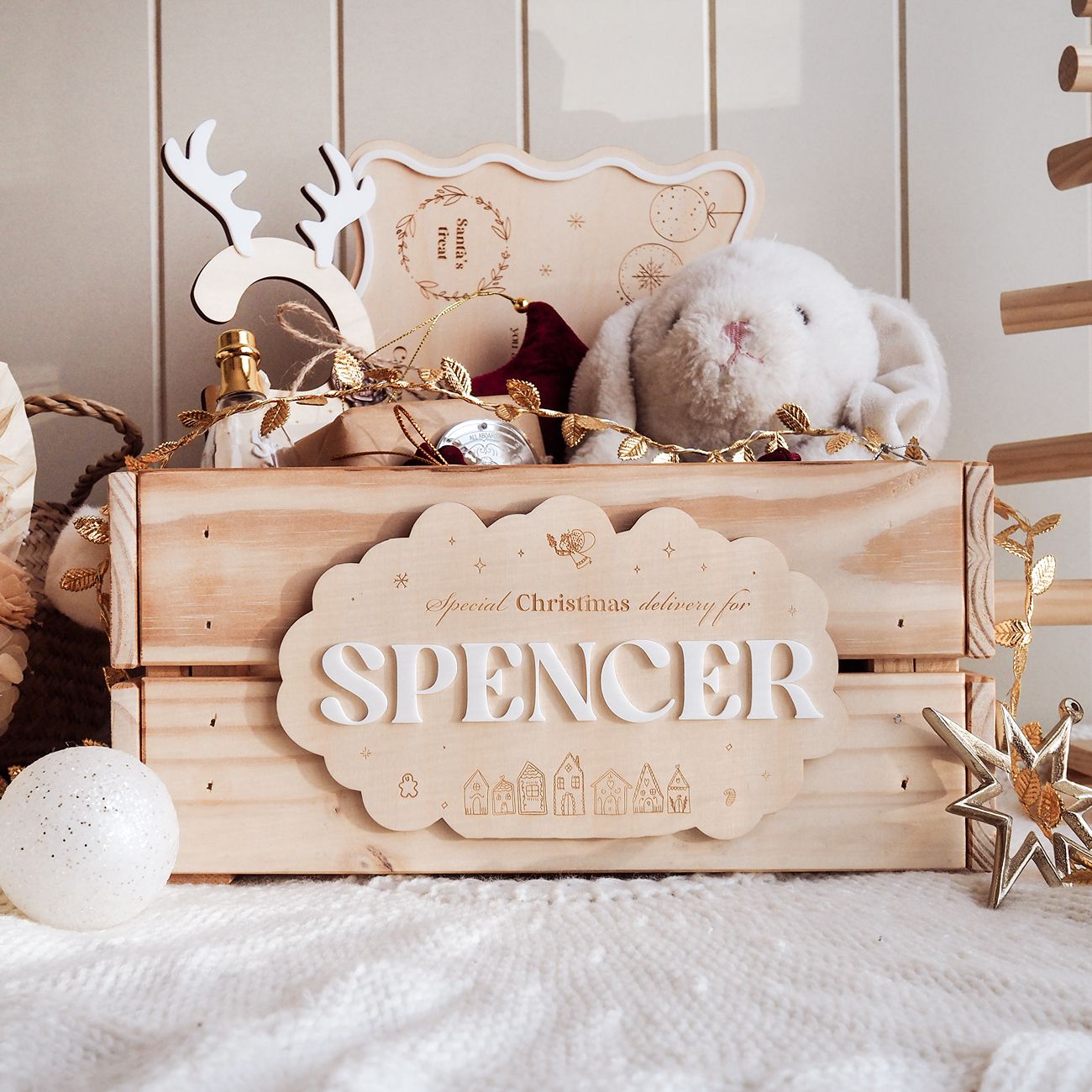 Wooden gift box with personalized name plaque, decorative items, and plush toys on a soft surface.