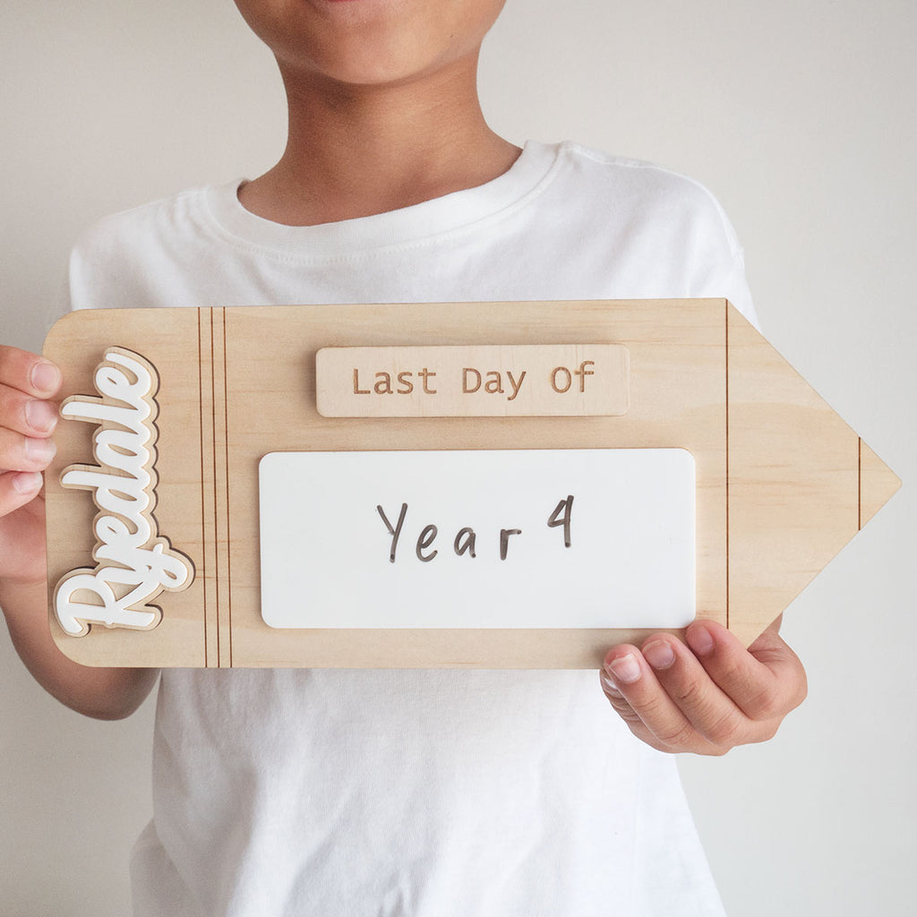 A boy is holding a First Day Of School Sign (Back to school photo prop). Photo is a closeup of the product