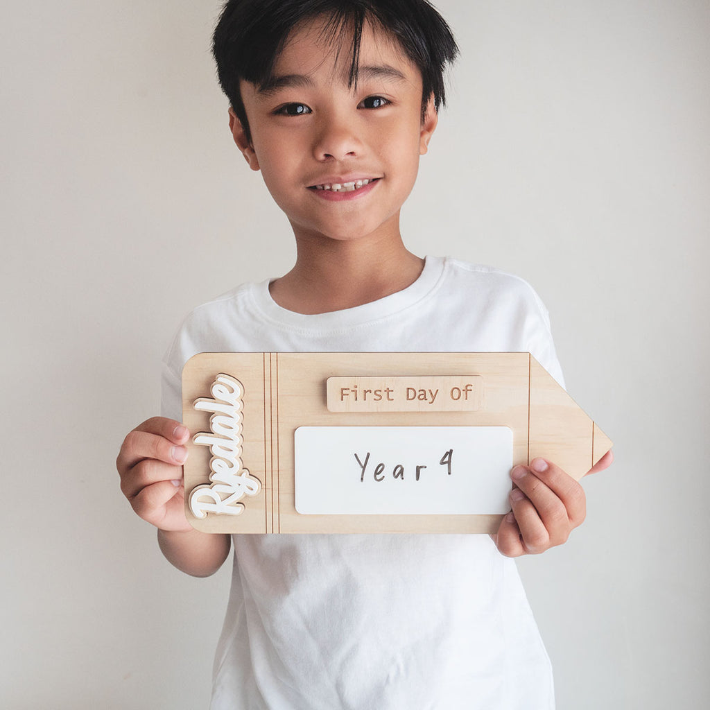 A boy is holding a First Day Of School Sign (Back to school photo prop). Half Body