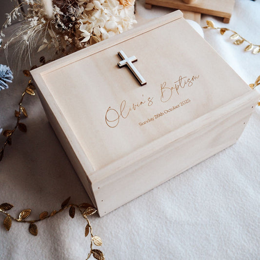 Wooden box with engraved text and a cross, surrounded by decorative elements on a light background