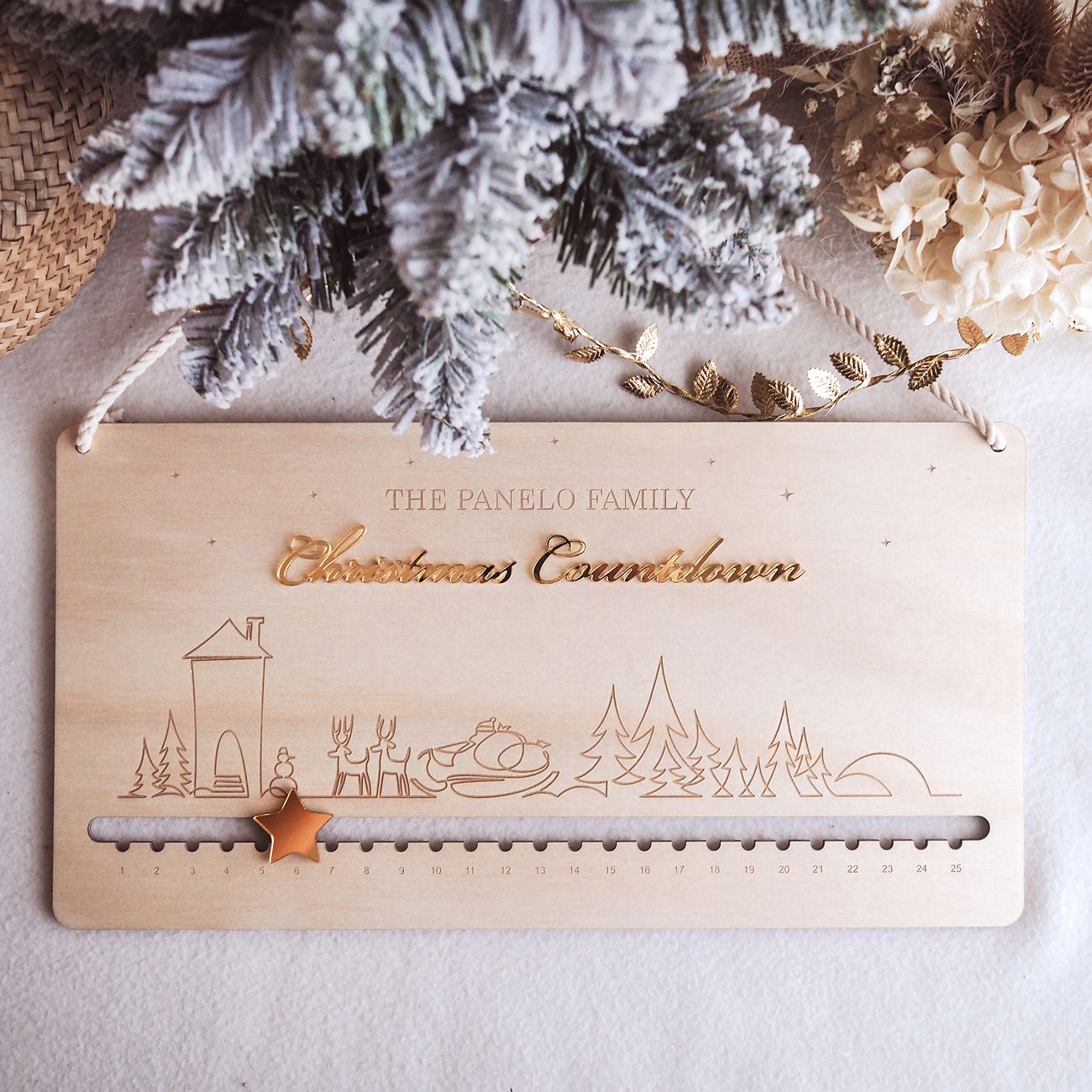 Wooden Christmas countdown calendar with family name and decorative elements on a light background