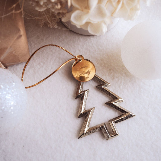 Decorative gold Christmas tree ornament with a gold tag on a white surface.