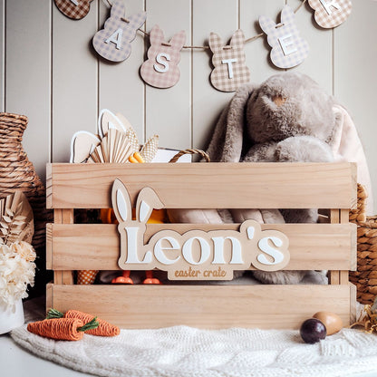 Wooden Easter crate with 'Leon's Easter crate' sign, stuffed bunny, and Easter decorations on a wooden background.