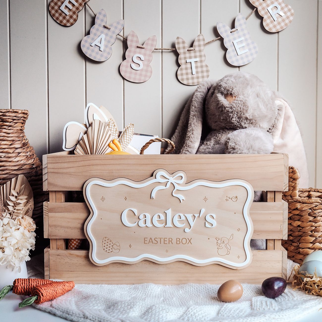 Wooden Easter box with 'Caeley's Easter Box' sign, teddy bear, and Easter decorations on a wooden background.
