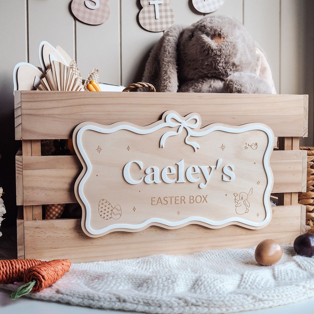 Wooden Easter box with a decorative sign reading 'Caeley's Easter Box' on a soft surface.