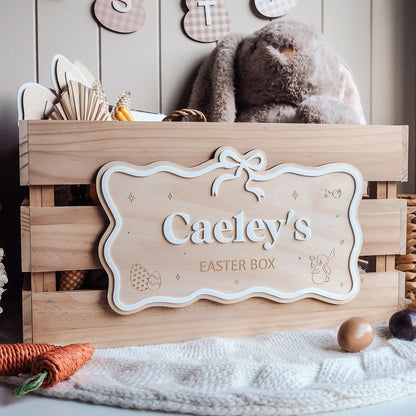Wooden Easter box with a decorative sign reading 'Caeley's Easter Box' on a soft surface.