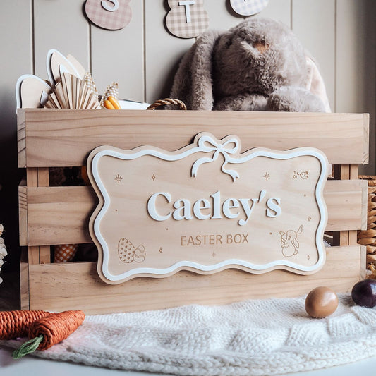 Wooden Easter box with a decorative sign reading 'Caeley's Easter Box' on a soft surface.