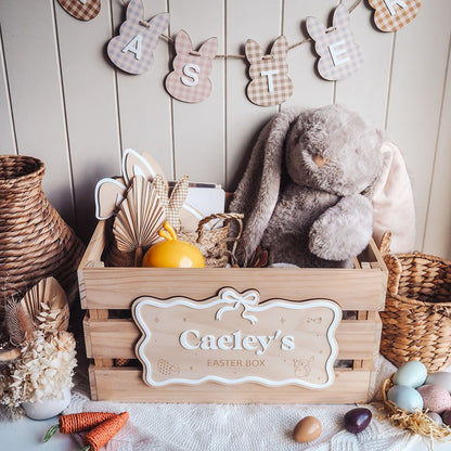 Wooden Easter box with a plush bunny, decorative eggs, and a banner on a wooden background