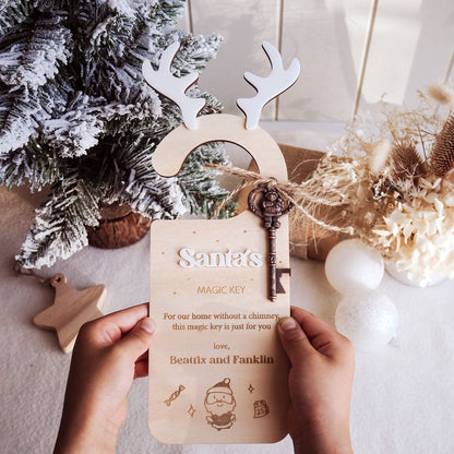 Wooden key-shaped ornament with reindeer antlers held by hands, Christmas tree and decorations in the background.