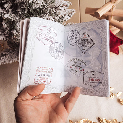 Passport with travel stamps held by a hand, Christmas tree in the background