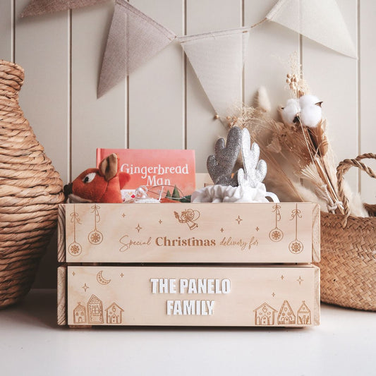 A personalised Christmas crate with interchangeable panels, featuring the name 'THE PANELO FAMILY' on the front, decorated with Christmas-themed decorations and filled with festive items.