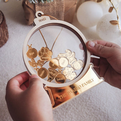 Decorative ornament with gold charms and 'The Paneo Family' engraving, held by a hand.